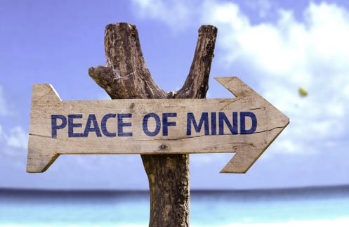 Peace of Mind wooden sign with a beach on background